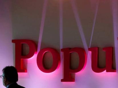 Un hombre pasando cerca del logotipo de Banco Popular