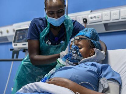 La enfermera de cuidados intensivos, Emily Chepng'eno (izquierda) coloca una máscara de ventilación mecánica durante una simulación para demostrar su funcionamiento tras la instalación de una moderna planta de oxígeno en el Hospital Metropolitano de la capital de Kenia, Nairobi, el 5 de mayo de 2021.