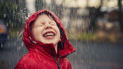 Un niño disfruta con entusiasmo de la lluvia.
