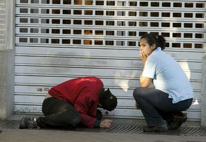 Dos trabajadores de un local de Madrid intentan abrir el cierre de la puerta, cuya cerradura había sido sellada con silicona.