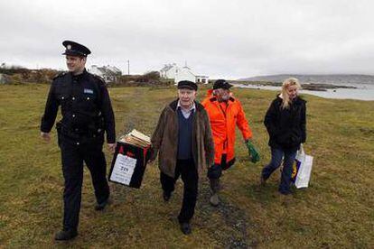 Un policía irlandés transporta una urna con el presidente de una mesa electoral en la isla de Innisfree.