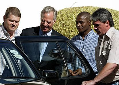 Mark Thatcher, de traje, sonríe al entrar en el coche tras ser detenido por la policía surafricana en Ciudad del Cabo.