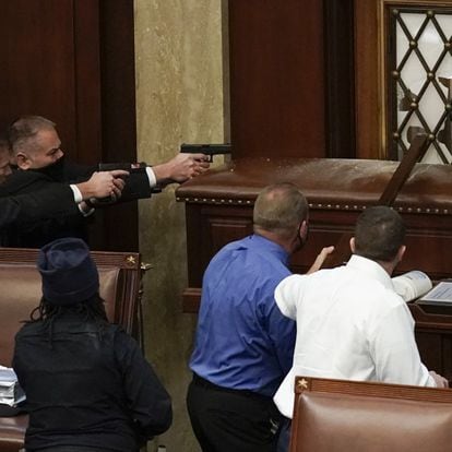 
La policía del Capitolio de los Estados Unidos con armas en la mano observa cómo los manifestantes intentan ingresar a la sesión en la sala principal del Capitolio 
