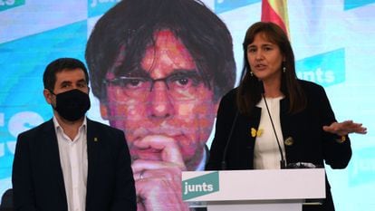 Laura Borràs, acompañada de Jordi Sànchez, frente a una pantalla con el rostro de Carles Puigdemomt.