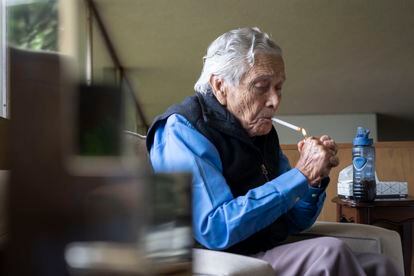 Hernández enciende un cigarro sentado en su sala, durante la entrevista.