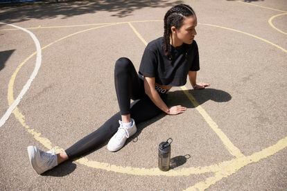 Sporty young woman on basketball court stretching