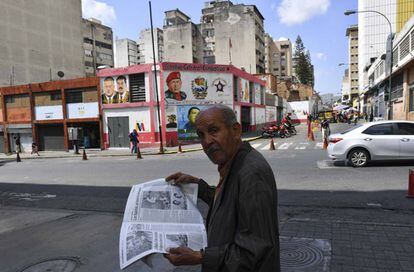 Un hombre lee un periódico, ayer en una calle de Caracas.