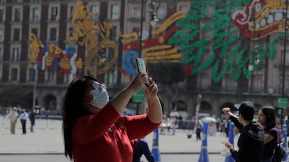 Una mujer toma una fotografía con su teléfono celular frente a la Catedral Metropolitana en el Zócalo de la Ciudad de México.