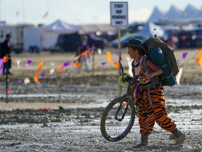 Un participante en el festival Burning Man lleva a pulso su bicicleta a través del barro tras la tormenta que dejó atrapadas a decenas de miles de asistentes.