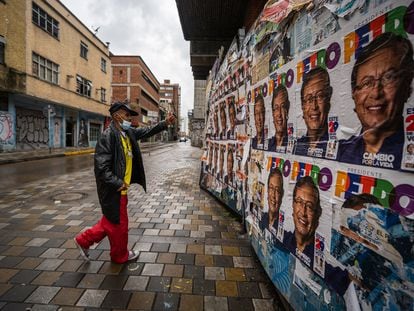 Un hombre hace un gesto de apoyo frente a carteles del candidato Gustavo Petro en las calles de Bogotá.