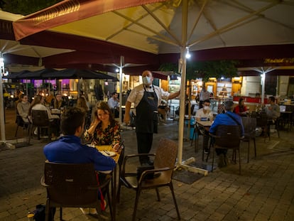 Un camarero enciende unas luces en la terraza de la Cervecería Alemana de la plaza de Santa Ana en Madrid.