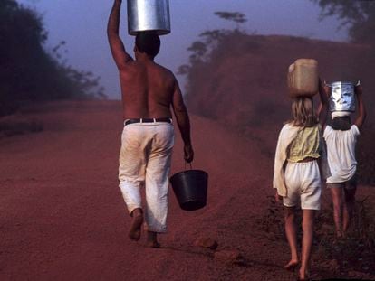 En noviembre de 2017, un padre camina con sus hijas cargando cubetas de agua por la carretera Transamazónica, en el Estado de Pará (Brasil).