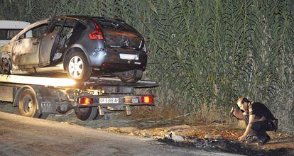 Un polic&iacute;a investiga el lugar en el que apareci&oacute; el veh&iacute;culo calcinado.