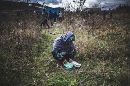 Un immigrant afghan mange à côté d'une file d'attente de personnes recevant de la nourriture de l'association d'aide aux migrants de Calais