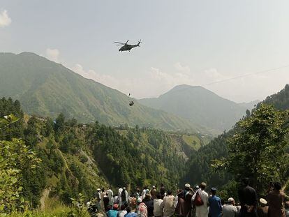 Rescate en helicóptero de uno de los menores de edad, del grupo de ocho personas, que este lunes quedó atrapado en un teleférico en Pakistán.