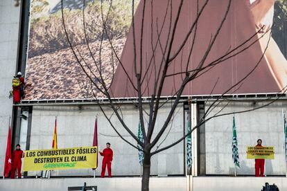 Varías personas de Greenpeace, vestidas con un mono rojo, sujetan carteles en los que denuncian los combustibles fósiles como causa de destrucción del clima. Mientras uno de ellos baja por la fachada del edificio. Imagen distribuida por la ONG.
