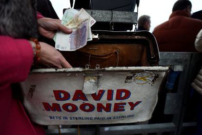 Un corredor de apuestas sostiene billetes de libras y euros en el hipódromo Punchestown en Naas.