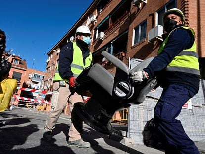 Dos operarios retiran los enseres durante el desalojo de las cuatro viviendas de la calle Presa en San Fernando de Henares (Madrid).
