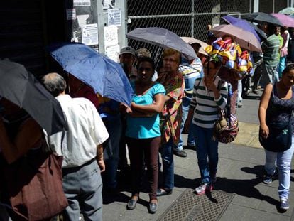 Un grupo de personas hace cola a las puertas de un supermercado en Caracas.