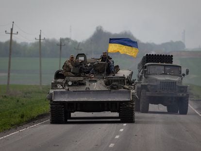 Un carro con una bandera de Ucraina junto a un camion lanzacohetes circulan por una carretera cercana a Lissitxansk.