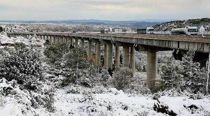 Varios camiones en el viaducto de Buñol junto a un paisaje nevado a solo 40 kilómetros de la ciudad de Valencia.