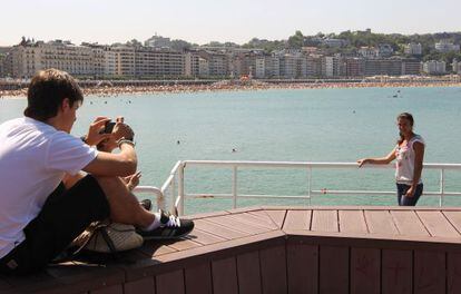 Una pareja de turistas se fotografía en la playa de La Concha de San Sebastián. 