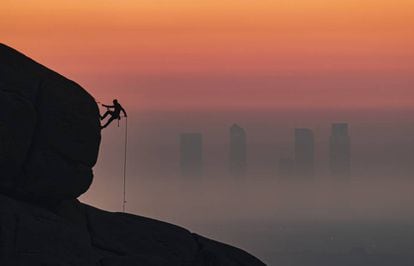 El bombero Antonio Marcos escala con las Cuatro Torres de fondo. Pincha sobre la imagen para ver más fotos de este 'skyline'.
