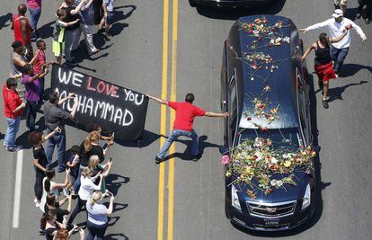 Un seguidor que porta un cartel intenta tocar el coche fúnebre del tres veces campeón mundial de boxeo en Louisville, Estados Unidos.