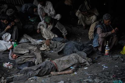 El cuerpo de un drogadicto yace mientras sus compañeros, casi ajenos a su muerte, siguen consumindo droga debajo del puente de Pul-e-Sukhta de Kabul.