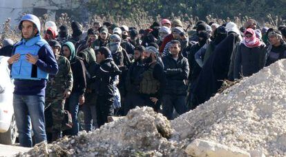 Civiles y soldados rebeldes esperan a ser evacuados de la ciudad siria de Homs tras un pacto con el régimen de El Asad.