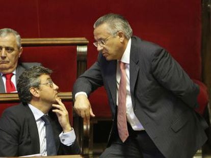 El concejal de Seguridad Ciudadana, Miquel Dom&iacute;nguez (de pie), habla con el de Juventud, Crist&oacute;bal Grau, durante el pleno de Valencia.