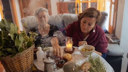 Pepa Amaya (a la izquierda) quema incienso junto a algunas de las hierbas con las que elabora un alcohol que regala como remedio natural. Junto a ella, su amiga María Jesús Fernández.