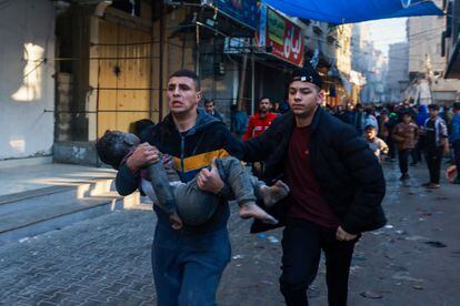 A Palestinian man runs with an injured child, after an Israeli bombing, this Friday in Rafah, after the truce between Israel and Hamas expired.