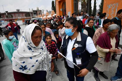 Habitantes de Santiago Xalitzintla hacen fila para recibir un kit de protección contra cenizas.