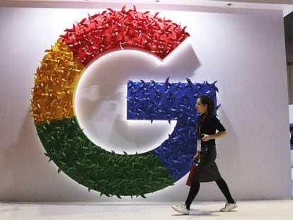 Una mujer camina delante del logo de Google.