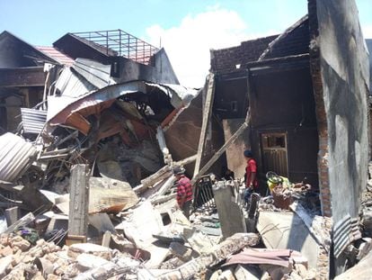 Ambo Pawe y sus dos hijos rebuscan entre las ruinas de su vivienda en el barrio de Balaroa (Palu).