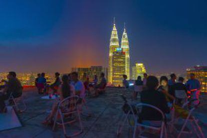 Las torres Petronas, iluminadas al fondo, vistas desde una terraza próxima, en Kuala Lumpur (Malasia).