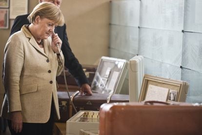 Merkel escucha un aparato de audio antiguo durante la visita ayer a una exposición en Berlín.