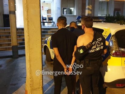 Un policía local con el uniforme roto lleva esposado a uno de los detenidos en Sevilla.