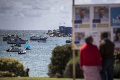 Varias personas observan carteles electorales en el puerto de A Guarda el pasado viernes.