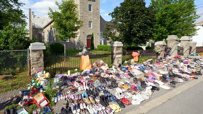 Flores y zapatos infantiles colocados frente a una iglesia en protesta tras el hallazgo de los restos de 215 niños en un orfanato.