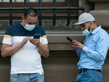 Dos hombres utilizan sus teléfonos móviles en el centro de Ciudad de México.