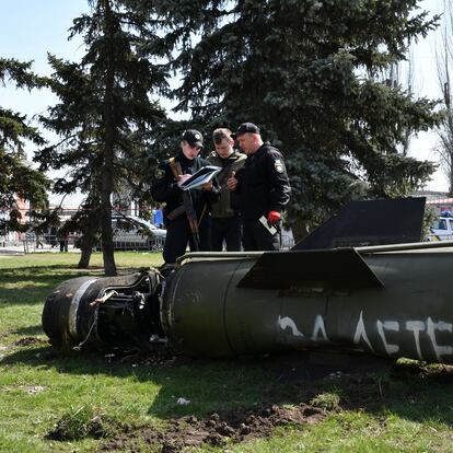 Ukrainian servicemen stand next to a fragment of a Tochka-U missile with a writing in Russian "for children" on a grass after Russian shelling at the railway station in Kramatorsk, Ukraine, Friday, April 8, 2022. (AP Photo/Andriy Andriyenko)