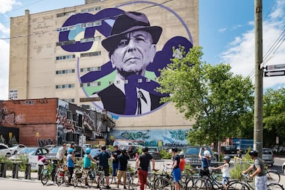 Ciclistas urbanos ante un retrato de Leonard Cohen en una medianera de Montreal, ciudad natal del cantante canadiense.