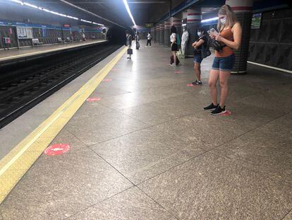 Los viajeros se sitúan en las marcas orientativas en los andenes de la estación Atocha Renfe de metro.