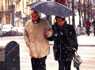 Unos viandantes cruzan una calle en Alcoi bajo la nieve protegidos por el paraguas.