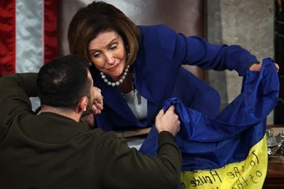 Zelenski intercambia unas palabras con la presidenta del Congreso, Nancy Pelosi, mientras le entrega la bandera de Ucrania.