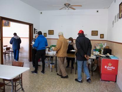 Una cocinera sirve comida en el comedor de Cáritas en Jaén, uno de los pocos abiertos para temporeros en la campaña de aceituna en Jaén.