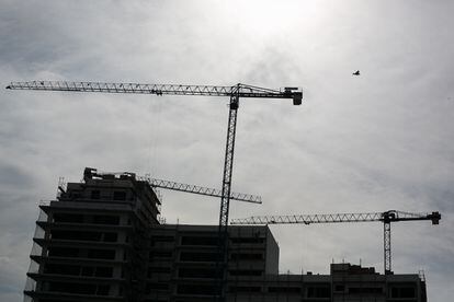 Grúas y edificio en construcción en contraluz de una promoción de viviendas en Barcelona
