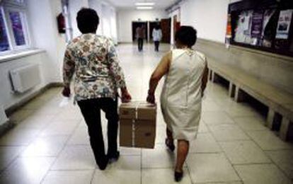 Dos funcionarias con una de las cajas que contienen los exámenes a médicos de primaria y matronas.EFE/Sergio Barrenechea